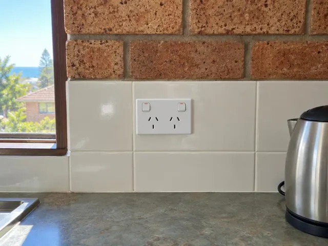 White double power point on tiled kitchen splashback with brick wall above and window nearby in Narrabeen