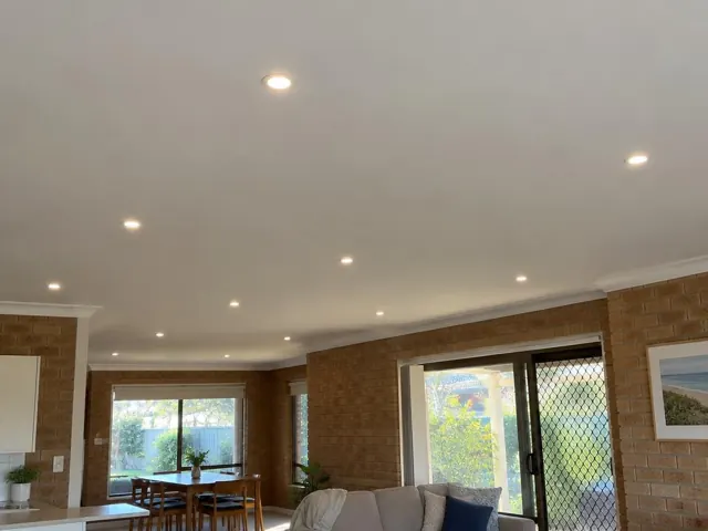 Living room ceiling with evenly spaced recessed downlights over brick walls and sliding doors in Cromer